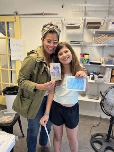 Participants in parent-child workshop show their printmaking.